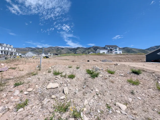 Expansive lot with mountain backdrop, surrounded by residential properties and a clear blue sky