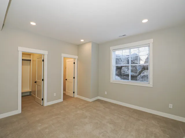 Carpeted room featuring recessed lighting, a window with blinds, and two entryways with white trim and black hardware