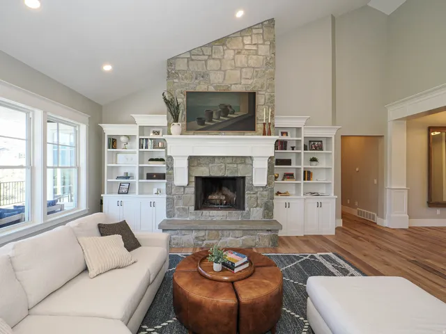 Great room featuring a floor-to-ceiling stone fireplace with a substantial mantel, flanked by built-in white cabinetry and shelving