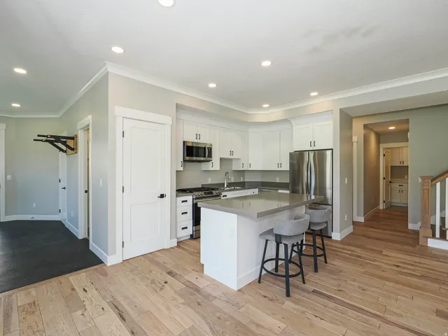 Modern kitchen featuring white cabinetry, stainless steel appliances, a center island with seating, and light-toned wood-finish flooring