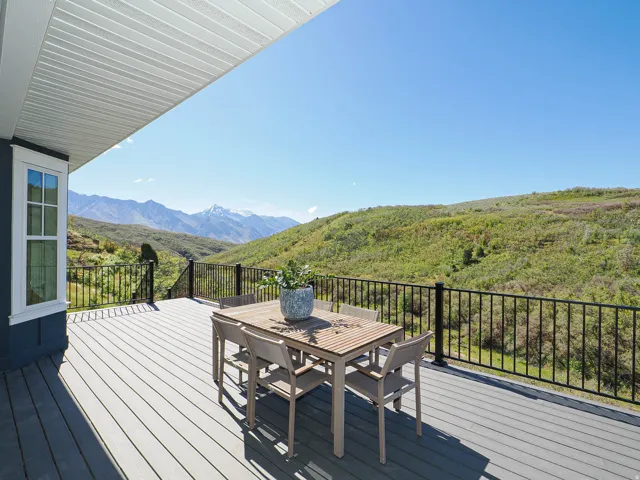 Expansive outdoor deck featuring composite decking, a black metal railing, and a vaulted ceiling