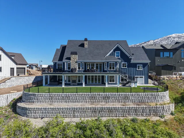 Rear exterior featuring dark blue vertical siding, a stone chimney, and multiple balconies with dark railings