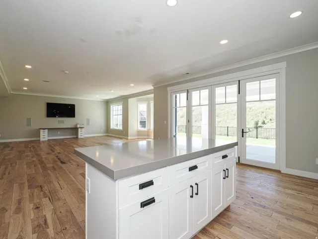 Kitchen island with a light-toned countertop and white shaker cabinetry featuring black hardware