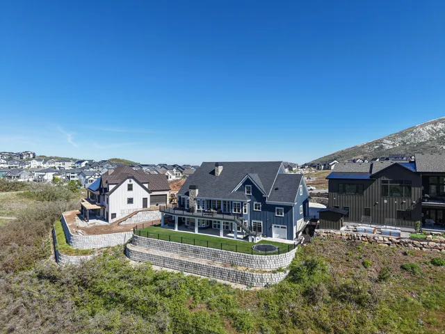 Contemporary blue siding residence featuring a dark shingled roof and multiple rear decks
