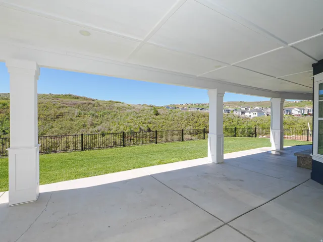 Covered concrete patio featuring white support columns and a coffered ceiling with recessed lighting