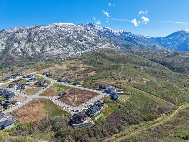Residential development featuring paved roadways and defined building lots, set against a mountainous backdrop with snow-capped peaks