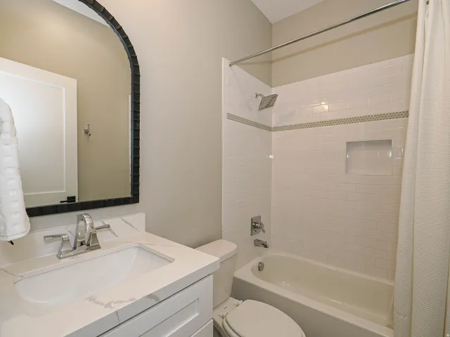 Bathroom featuring a white subway tile shower with a recessed niche, a rain shower head, and a decorative mosaic accent band