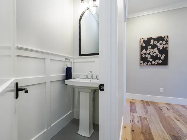 Pedestal sink with chrome fixtures and an arched mirror