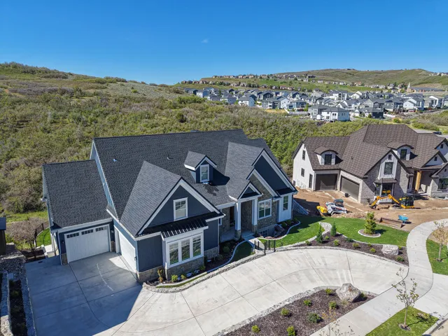 Modern Craftsman-style home featuring a dark blue exterior with white trim, stone accents, a multi-gabled roof, and an attached two-car garage