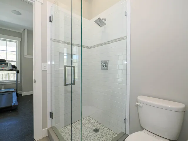 Glass-enclosed shower featuring subway tile surround, decorative mosaic accent band, built-in shower niche, and hex tile flooring