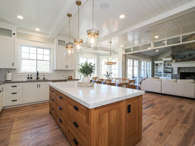 Spacious kitchen featuring a large wood-finish island with a light-toned countertop, white cabinetry, and wood-finish flooring