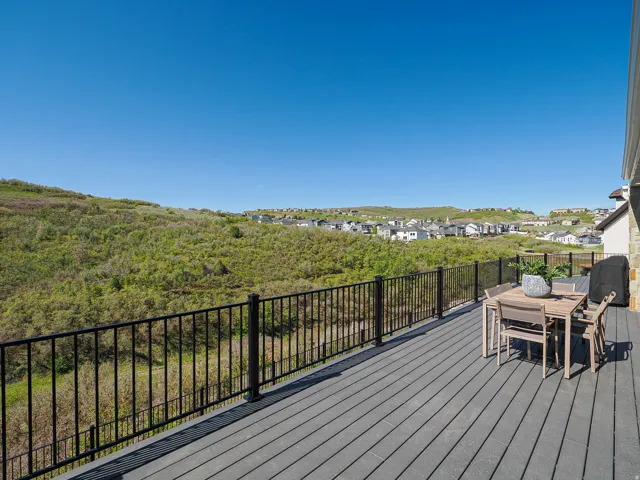 Spacious deck featuring composite decking, black metal railings, and a stone facade on the property