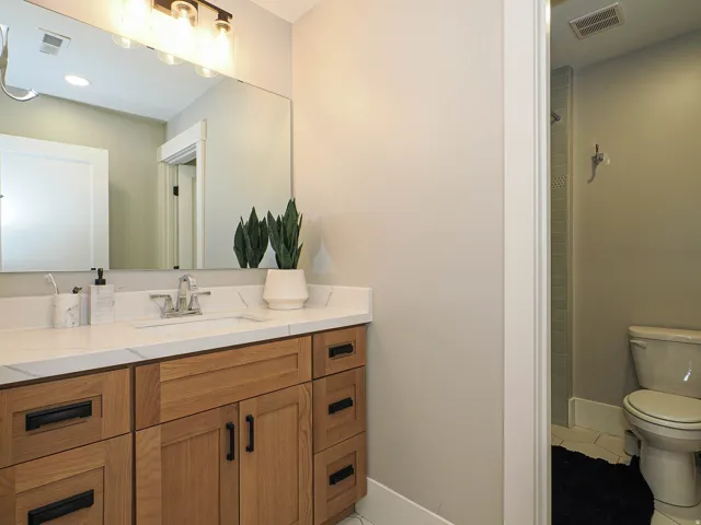 Bathroom vanity featuring a quartz countertop with an integrated sink, wood-finish cabinetry, and matte black hardware