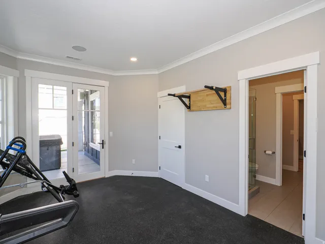 Spacious room featuring durable dark rubber flooring, white trim, and a built-in wooden pull-up bar