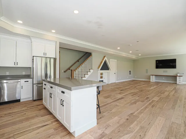 Open-concept living space featuring wood-finish flooring, recessed lighting, and crown molding
