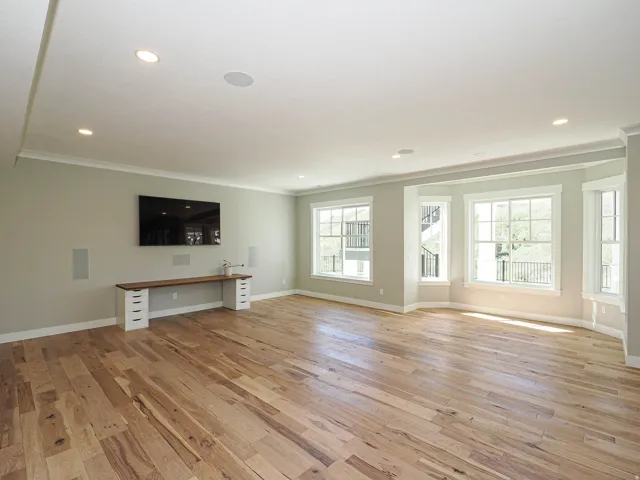 Spacious room featuring wide plank wood-finish flooring and ample natural light from multiple windows, including a bay window
