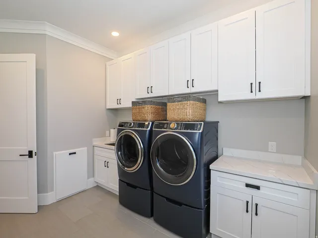 Laundry room with white shaker cabinetry, light-toned flooring, and integrated countertop space