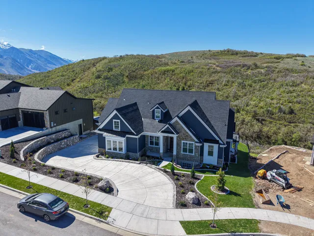 Contemporary residence featuring a dark blue siding and stone facade, multi-gabled roofline, and a concrete driveway