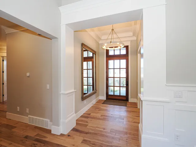 Entryway featuring wood-finish flooring, a wood-paneled front door with multiple lites, a tray ceiling, and wainscoting
