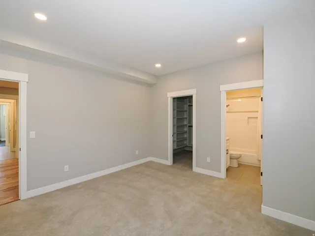 Carpeted room featuring recessed lighting, a built-in closet with shelving, and a full bathroom with a tub/shower combination