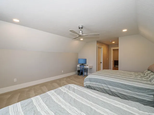 Carpeted room featuring a sloped ceiling, recessed lighting, and a modern ceiling fan