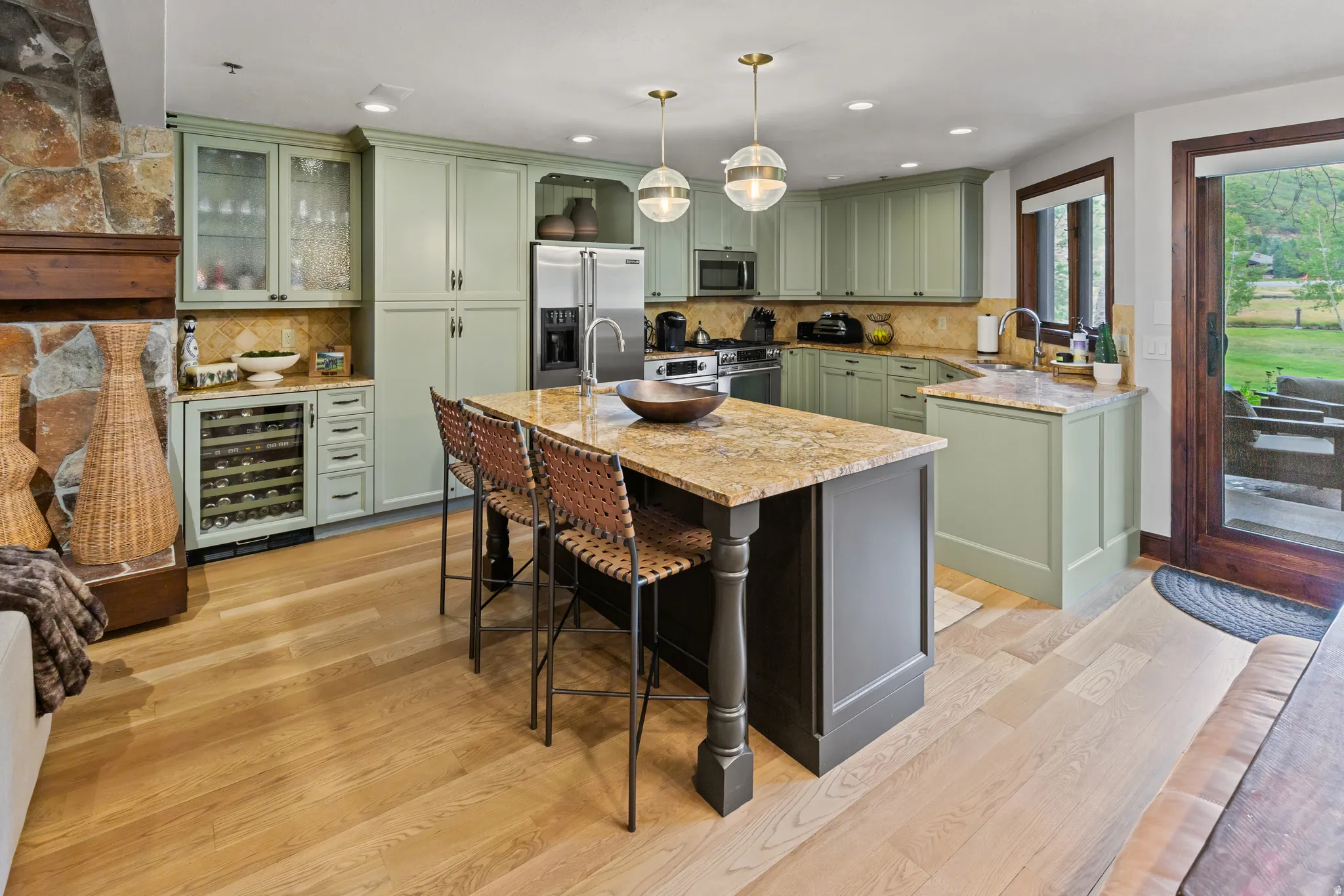 Open-concept kitchen featuring pale green cabinetry and a central island with granite countertops