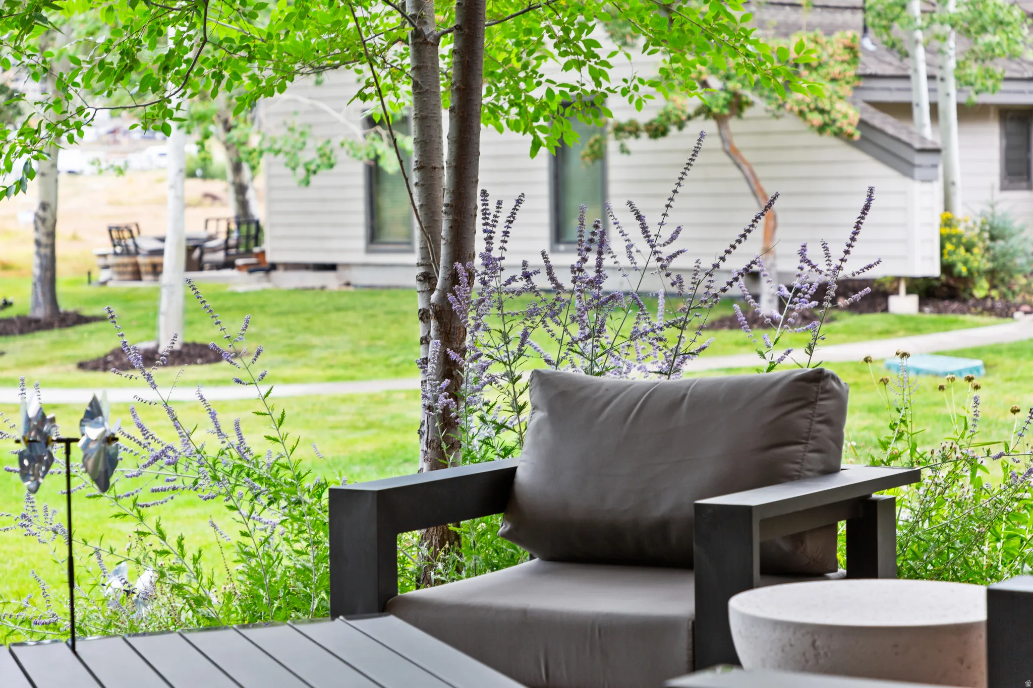 Expansive outdoor patio featuring a durable composite deck, surrounded by mature trees and lush plantings