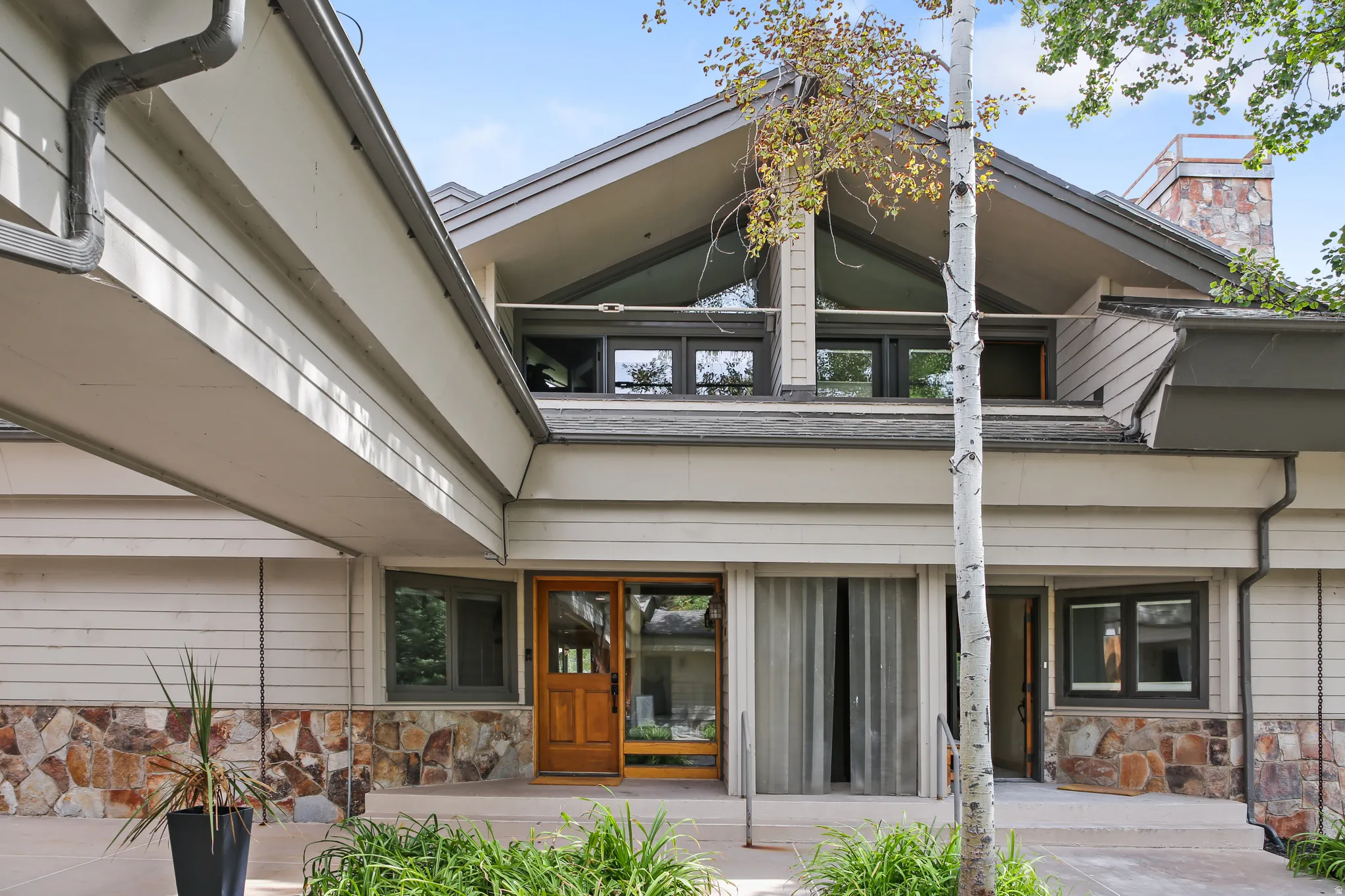 Contemporary architectural style featuring a prominent gabled roofline and natural stone veneer
