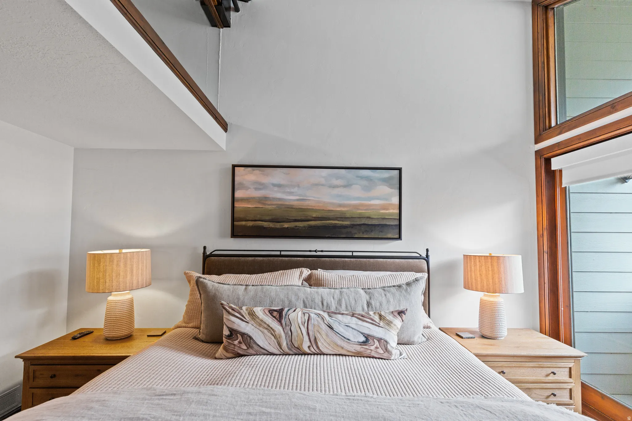 Loft-style bedroom featuring high ceilings and exposed wood beams