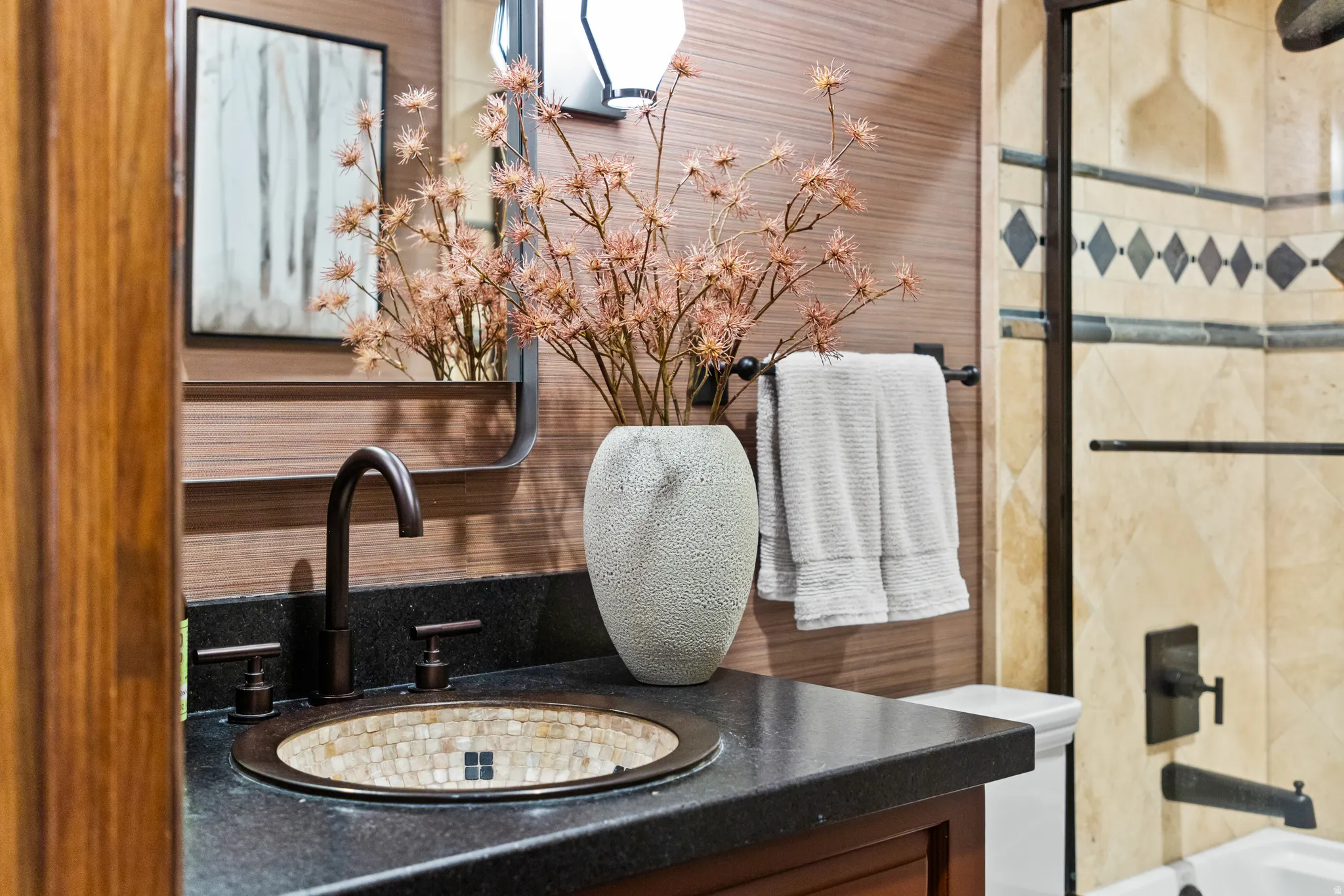 Vanity featuring a mosaic-tiled basin, dark stone countertop, and oil-rubbed bronze fixtures