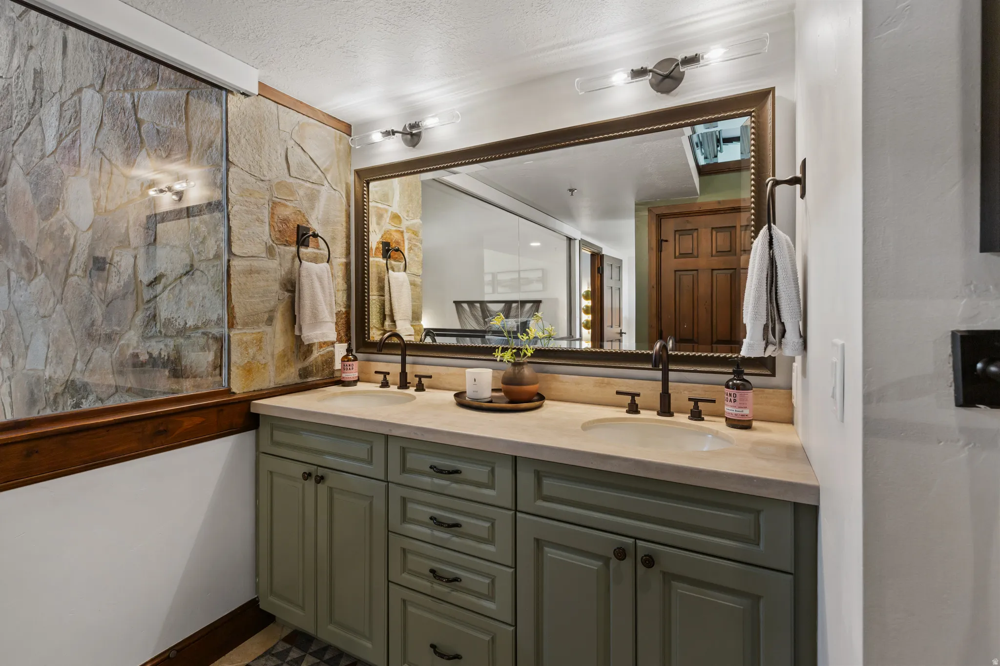 Double vanity featuring a light stone countertop, dual undermount sinks, and oil-rubbed bronze faucets