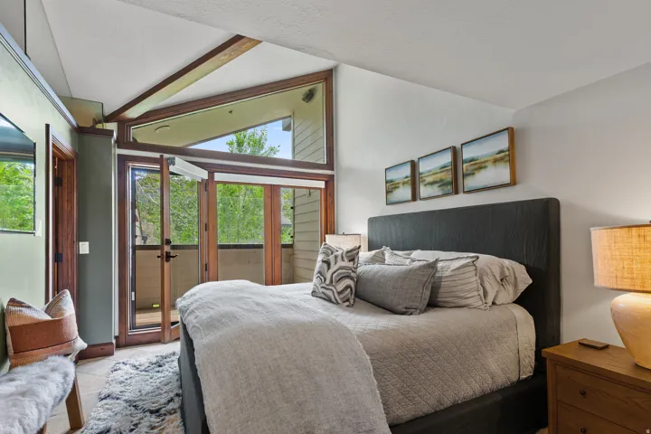 Bedroom featuring expansive glass doors, wood-frame windows, and a private balcony