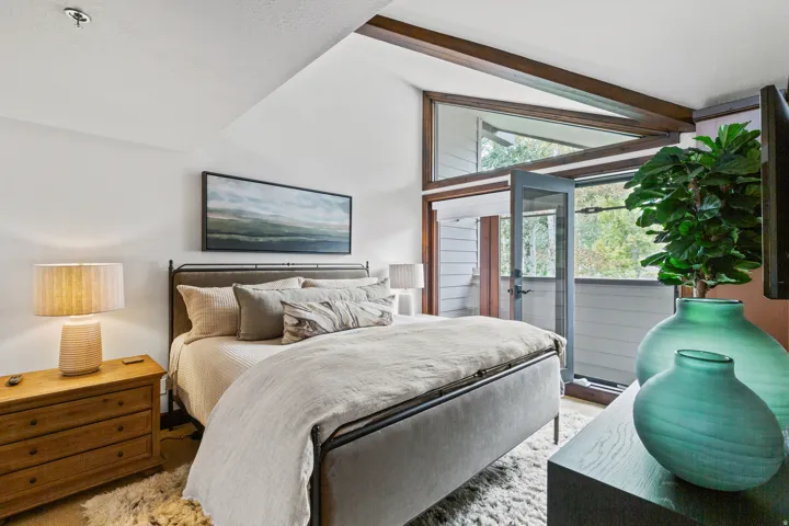 Vaulted ceilings with exposed wood beams, a full glass door to exterior, and high transom windows