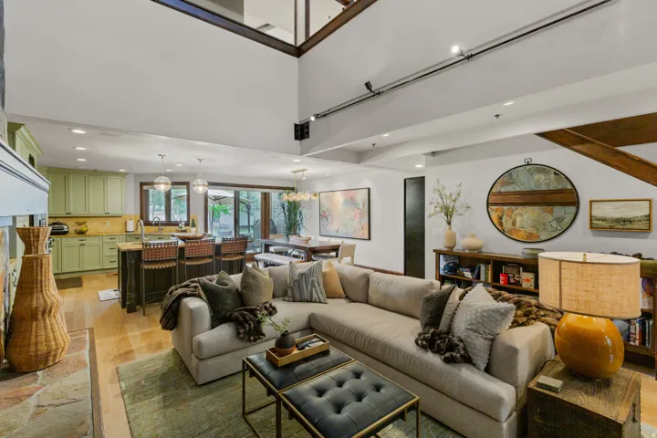 Expansive open-concept living area featuring a stone-clad fireplace and wood-finish flooring