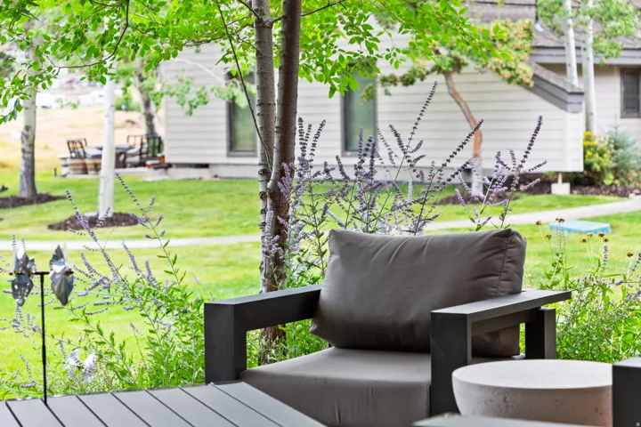 Expansive outdoor patio featuring a durable composite deck, surrounded by mature trees and lush plantings