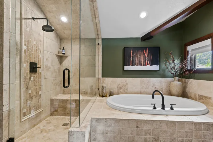 Spacious bathroom featuring a glass-enclosed shower with a built-in bench and rain showerhead