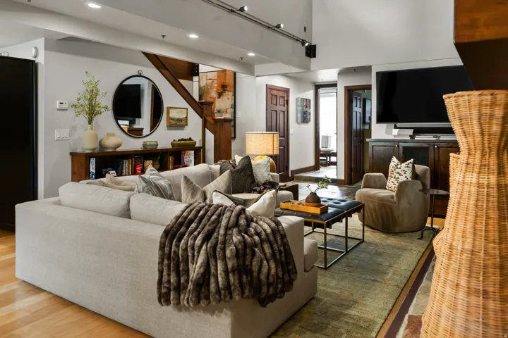 Living area featuring wood-finish flooring, recessed lighting, and a prominent built-in media console