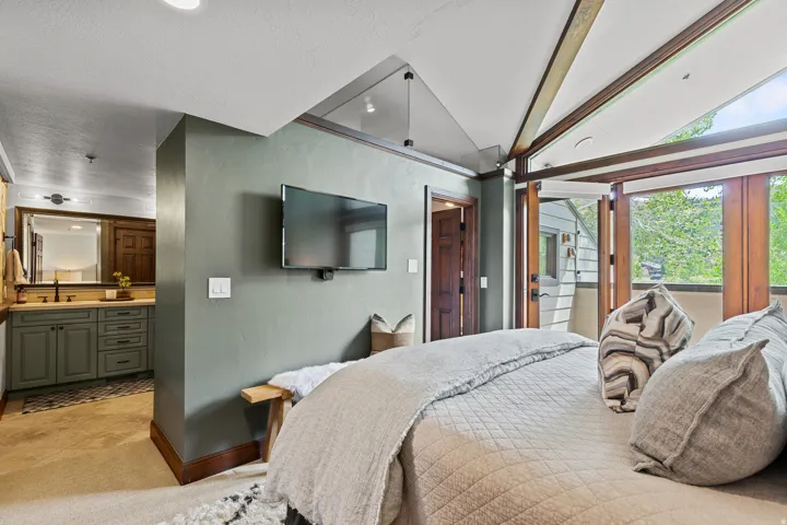 Bedroom featuring a wood-finish vaulted ceiling, a wall-mounted television, and direct access to an outdoor space via folding glass doors