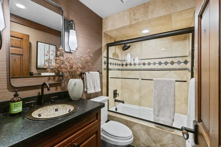 Bathroom featuring a stone countertop vanity with mosaic basin, a framed wall mirror, and a wall-mounted light fixture
