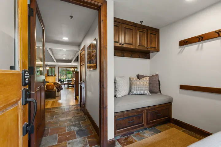 Entryway featuring slate tile flooring, a wood-paneled door with dark hardware, and a built-in mudroom bench with storage drawers