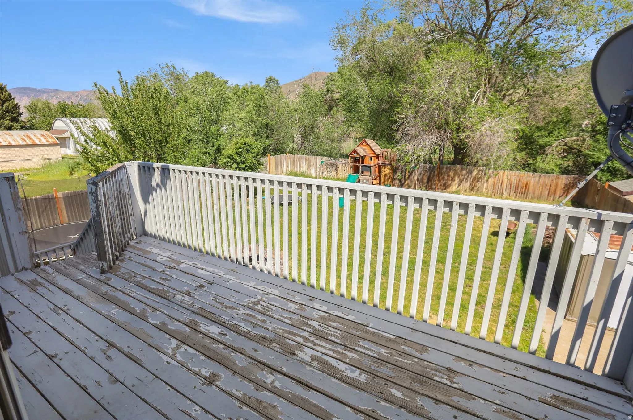 Spacious outdoor deck overlooking a fenced backyard with mature trees