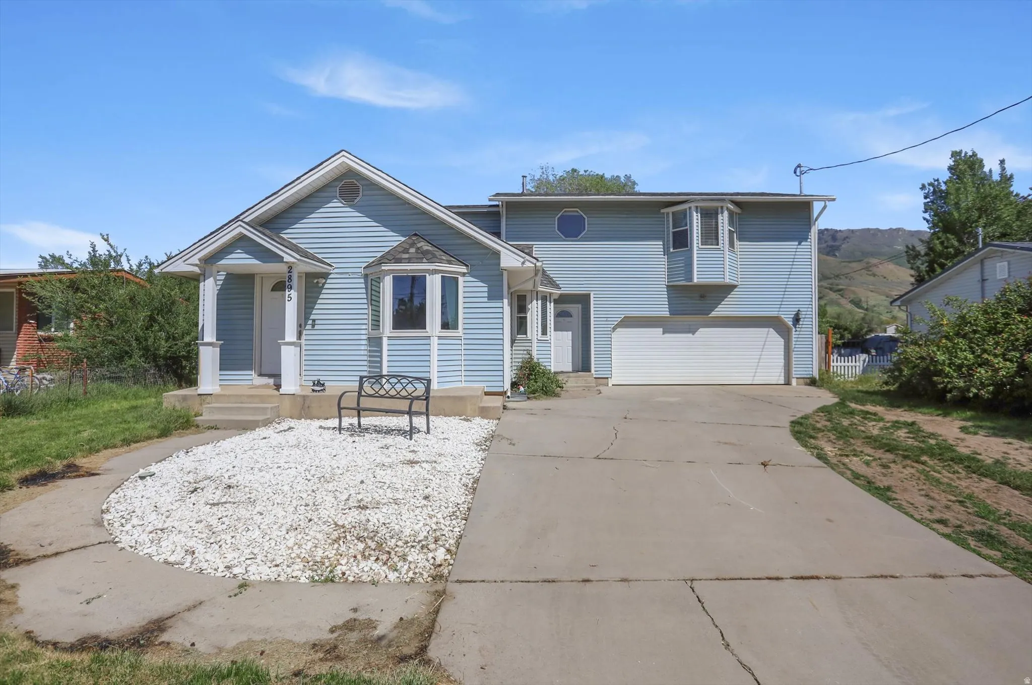 Blue horizontal vinyl siding exterior featuring a white garage door, a bay window, and a circular window