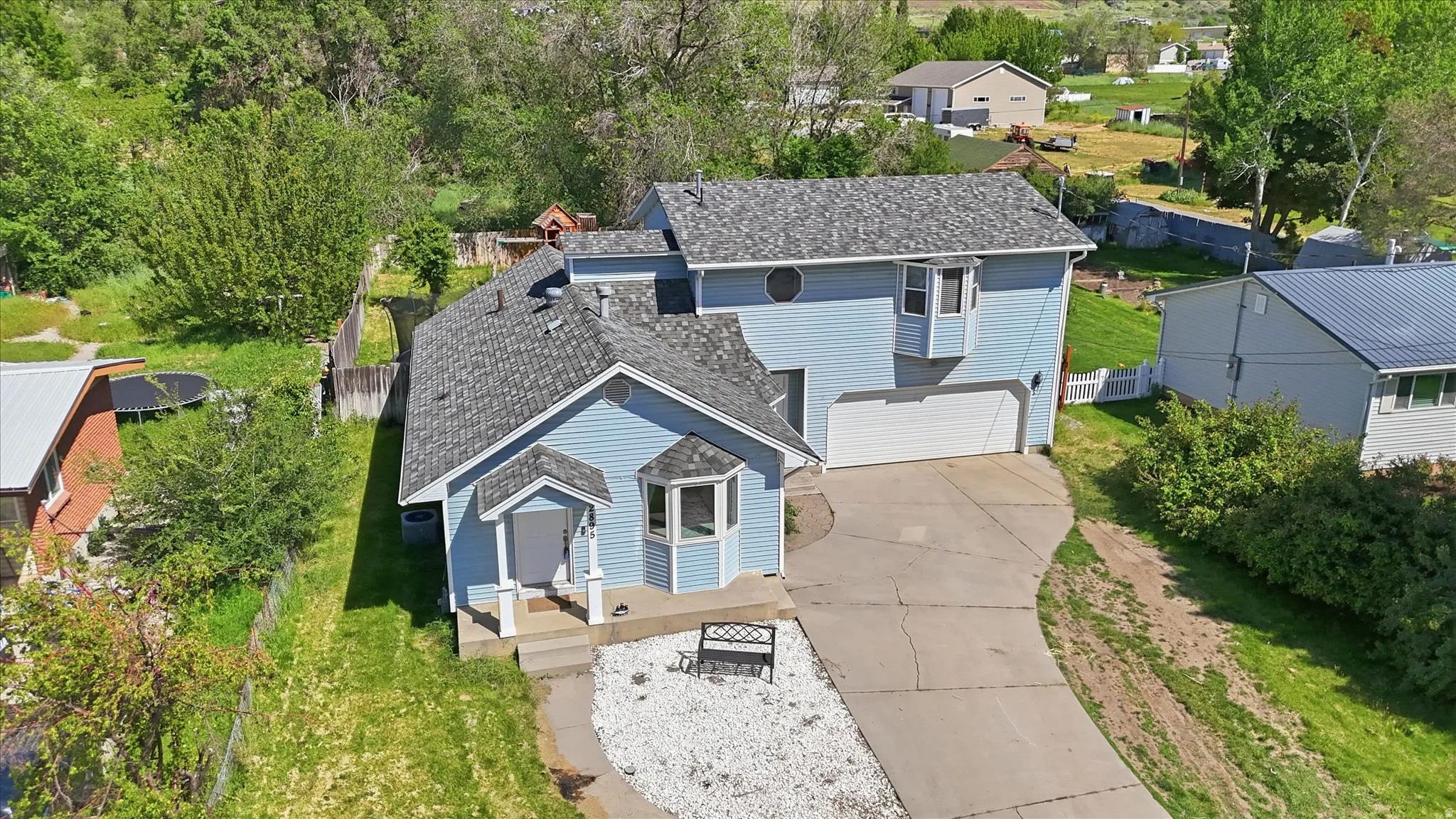 Light blue siding residence with a bay window, covered porch entry, and an attached two-car garage