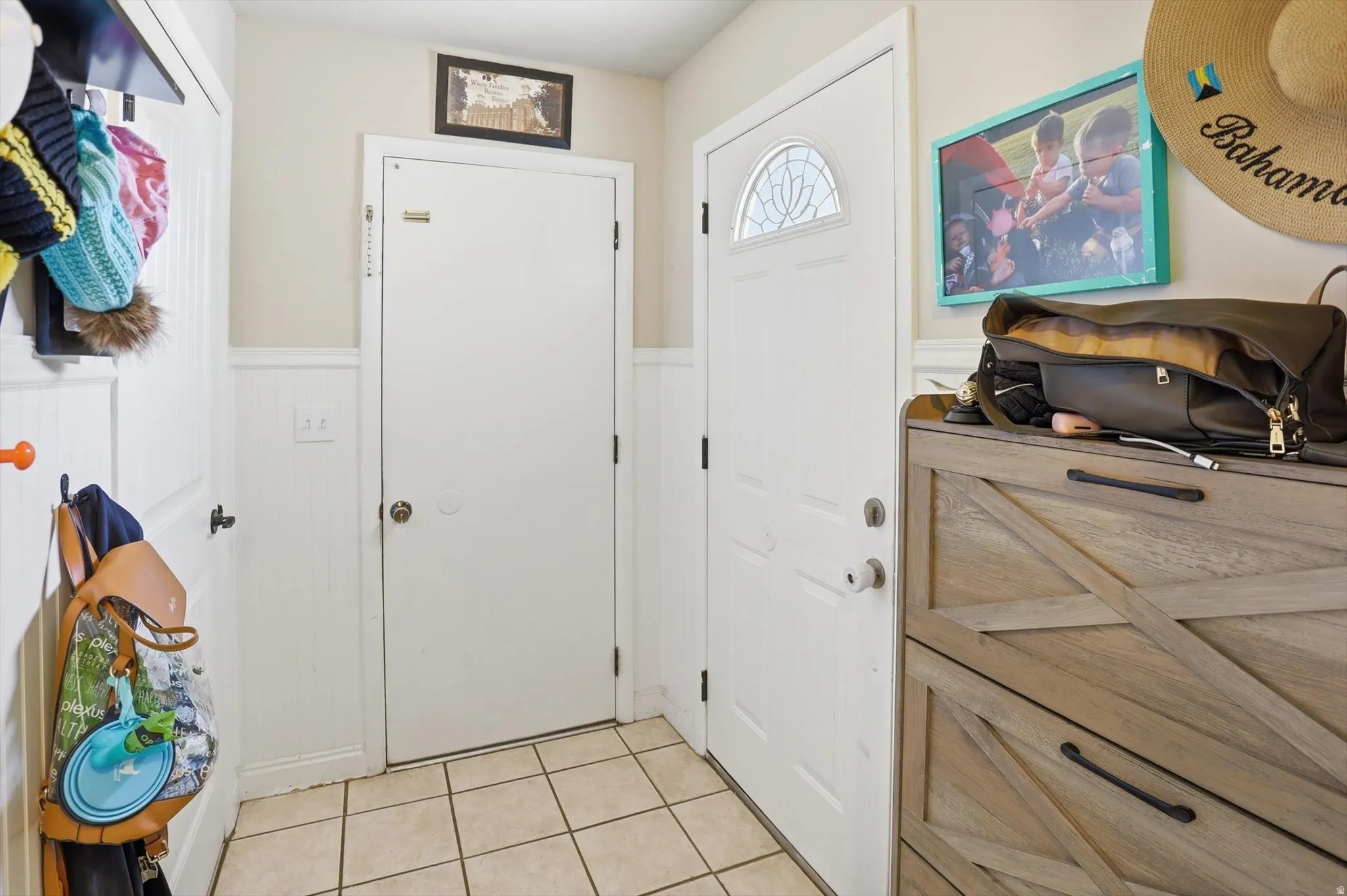 Entryway featuring a white paneled door with an arched decorative glass insert and ceramic tile flooring