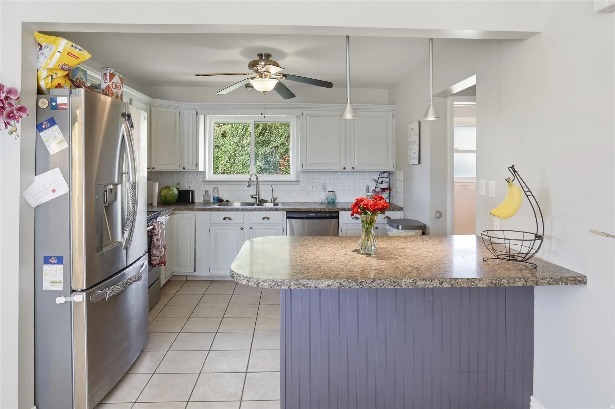Kitchen featuring white cabinetry, granite-finish countertops, tile flooring, and a stainless steel refrigerator