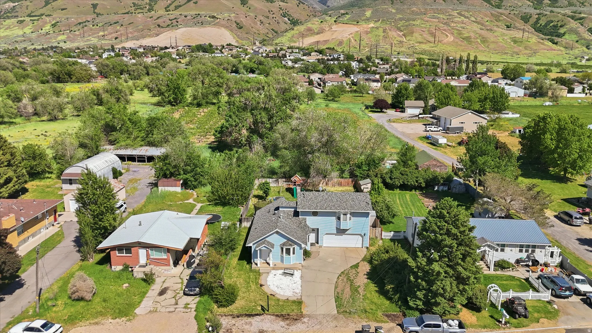 Light blue residence with a pitched roof, attached garage, and a concrete driveway