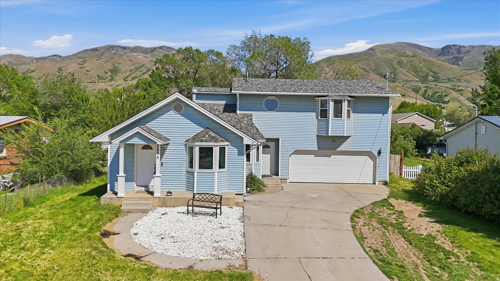 Two-story residence featuring light blue siding and a multi-pitch shingle roof