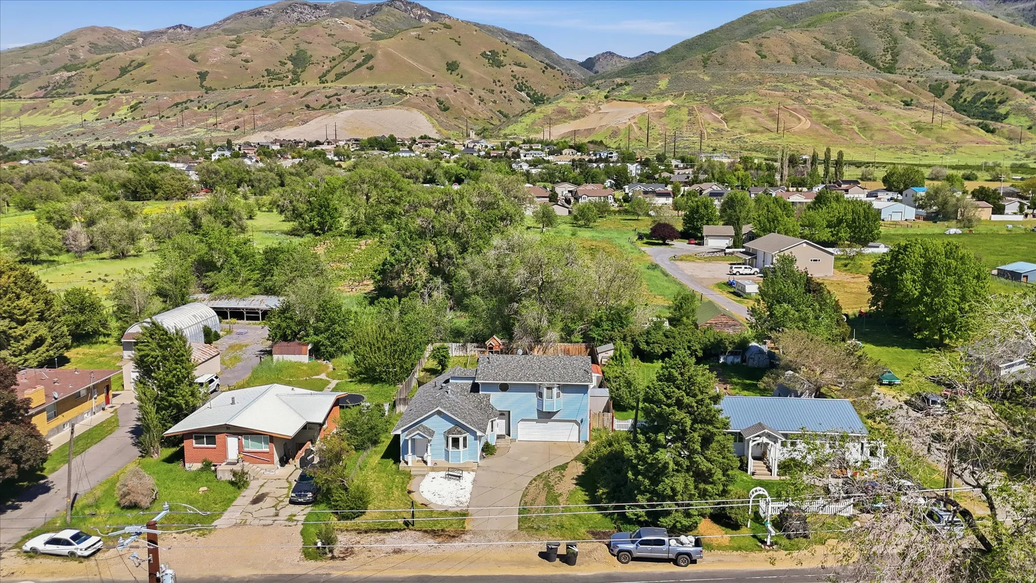 Aerial perspective showcasing a residential property with a light blue exterior and white trim, featuring an attached garage and a concrete driveway