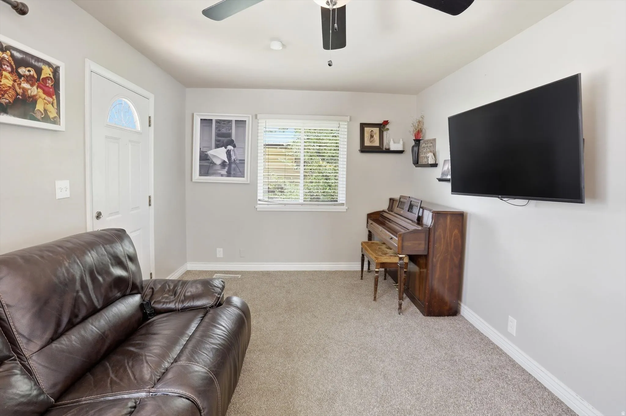 Carpeted living space featuring a window with blinds, ceiling fan, and light gray wall paint