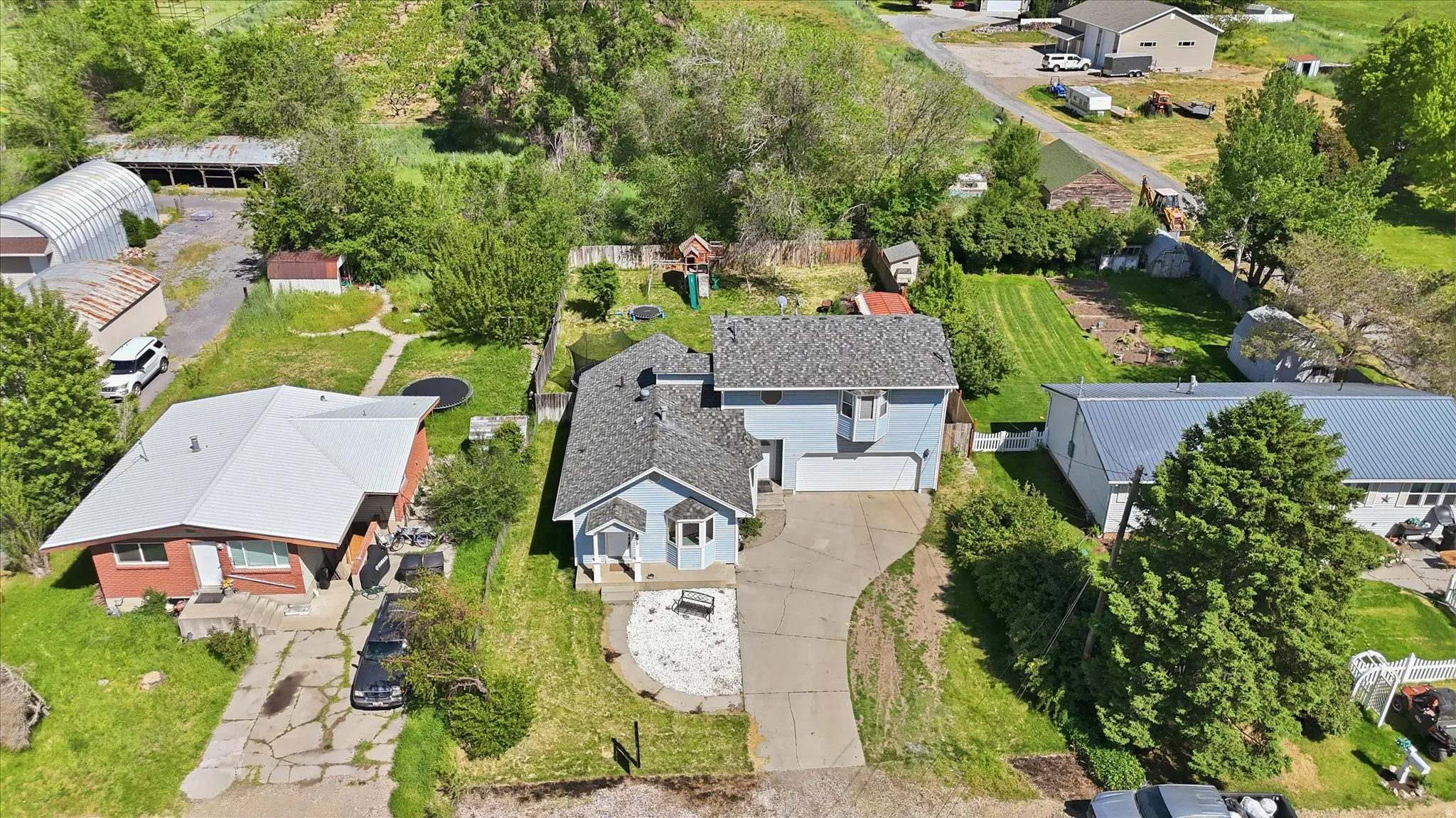 Light blue siding residence featuring a two-car garage, front porch, and a gravel driveway